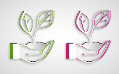 Paper cut Hand hold a leaf of the plant icon isolated on grey background. Care nature. Leaf shoots with environmental protection. Paper art style. Vector