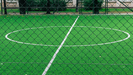 The center of an empty soccer field with an artificial green turf. The marking of the center of the soccer stadium
