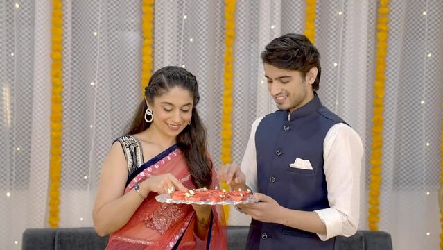 Indian couple enjoying Diwali by burning diye