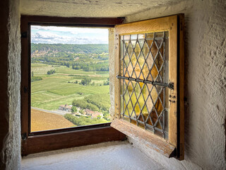 A square open window in a castle looking over green fields in the Dordogne valley in the south of France.