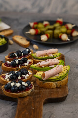 Sweet and savory snacks served on a wooden board on a gray background.
