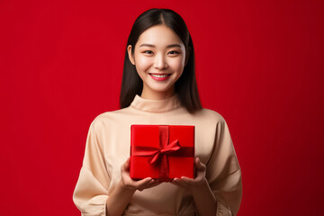 Fototapeta premium An Asian woman in a red uniform prepares a package for delivery next to a parcel post box. This image features a cheerful delivery woman against a vibrant red background. Generative AI.