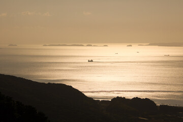 Fototapeta premium 夕暮れ時の黄金色に輝く海と漁船