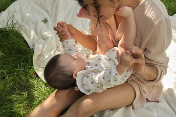 Close-up showcasing the purity of a mother's love as she softly kisses her newborn's feet,...