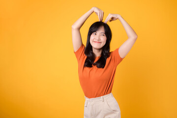 Warmth and authenticity shine through as a cheerful Asian woman in her 30s embraces love with a heart-shaped gesture and an infectious smile.