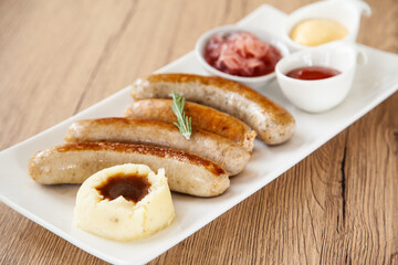 Four mixed grilled sausage with mashed potato and pickle
