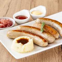 Fototapeta na wymiar Four mixed grilled sausage with mashed potato and pickle