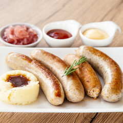 Four mixed grilled sausage with mashed potato and pickle