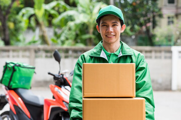 Asian smile rider in green uniform deliver parcel box by motorbike