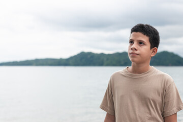 latin teenager looking at the horizon, wearing khaki sweater