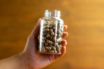 Jar of herbal dietary supplements held in hand, health improvement, drug dosage