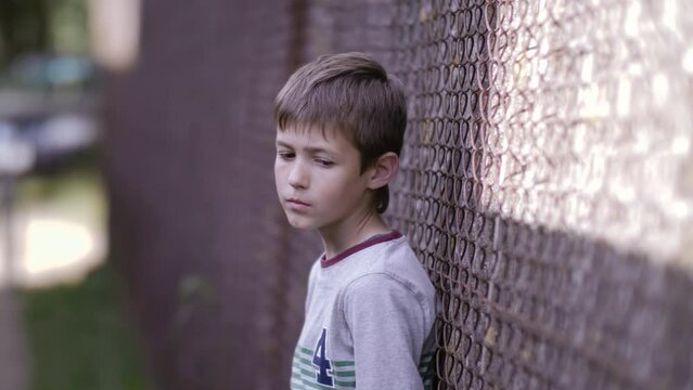 Contrasting Emotions: Sad Boy Stands on the Street and Gazes into the Camera, Remorseful Troublemaker Regrets His Actions