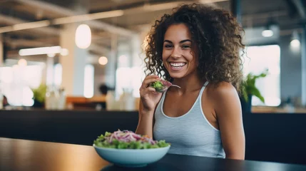 Foto op Aluminium Young athletic woman eats a salad in her plate while eating breakfast © MP Studio
