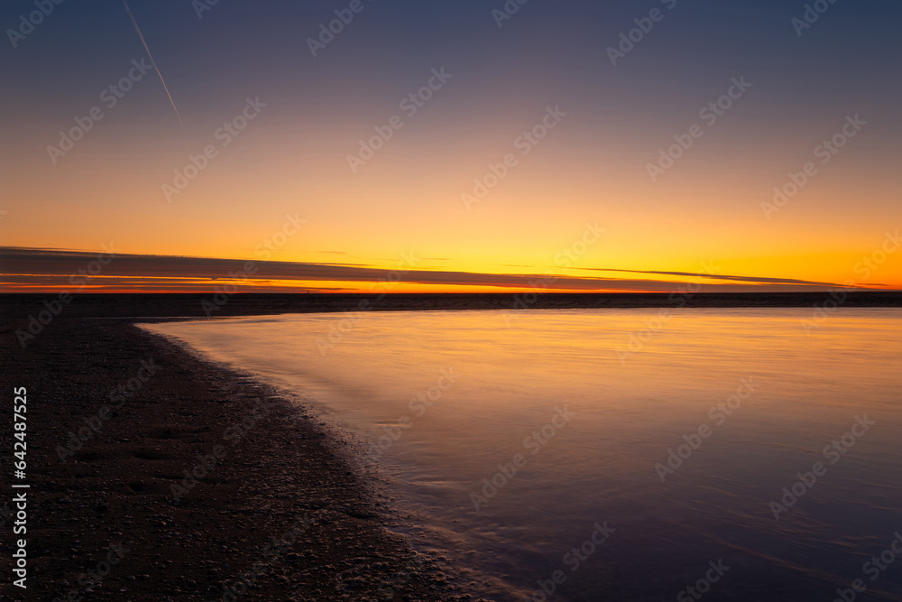 Wall mural a seascape during sunset. sand on the seashore. bright sky during sunset. a sandy beach at low tide.