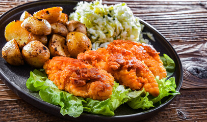 Breaded chicken cutlets served with potatoes and cabbage