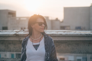 Obraz premium beautiful woman artist portrait with sunglasses in the golden hour on a building rooftop