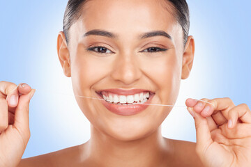 Woman, portrait and floss teeth in studio for healthy dental care, gingivitis and plaque on blue...