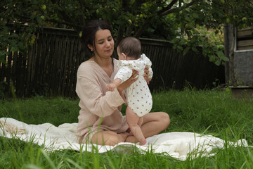 jubilant mom cuddles her infant, absorbing the serenity of their garden setting, exemplifying...