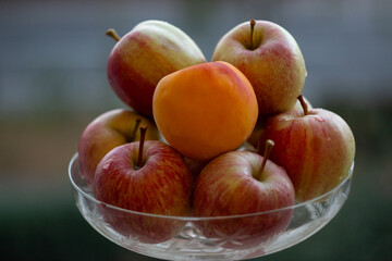 apples and peach in a glass vase