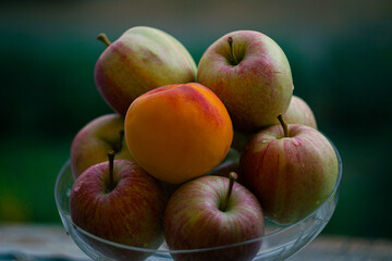 apples and peach in a glass vase