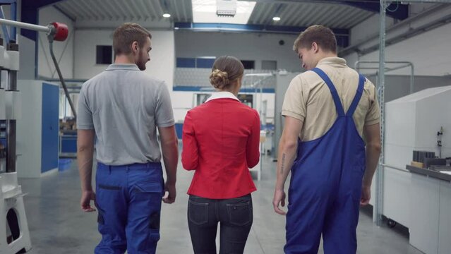 Worker and manager on factory floor discussing product specifications looking at a plan sheet