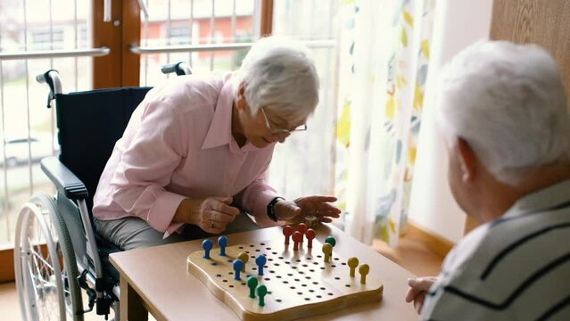 Two seniors, man and woman, in a nursing home playing a board game