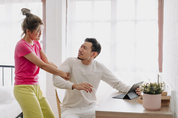 Fototapeta premium Asian wife asking husband to stop working and watching with computer tablet.