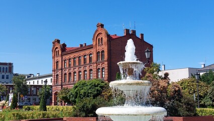 fountain in the park in front of old red brick building