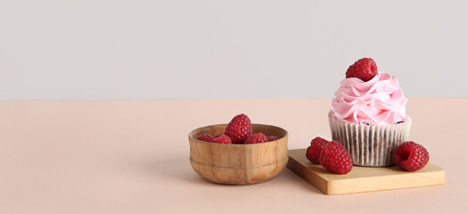 Tasty cupcake with raspberry on light background with space for text