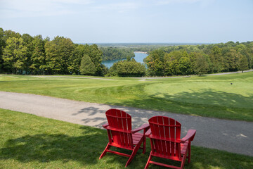View of Green Lakes in Syracuse from the golf course.  Looking down onto the lake with 2 red outdoor chairs in the foreground. No people. 