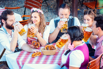 Group of women and men in Bavarian Beer garden drinking from glasses