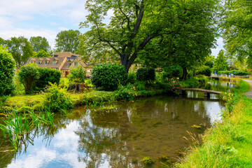 Fototapeta na wymiar The narrow River Eye as it runs past cottages and homes in the rural Cotswold District at the picturesque village of Lower Slaughter, Cheltenham, Gloucestershire, England, UK.