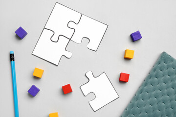 Paper puzzle pieces with cubes and notebook on light background. Logic concept
