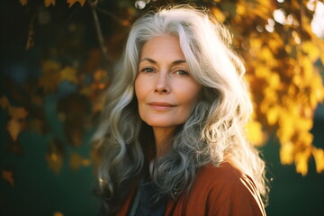 Smiling middle age grey-haired woman on the beach. Autumn