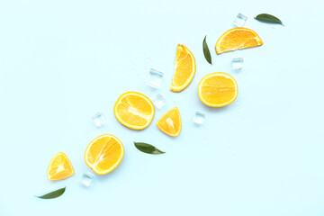 Cut orange with ice cubes and leaves on blue background