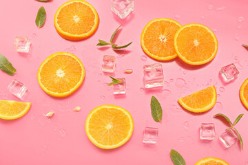 Orange slices with water drops, mint and ice cubes on pink background