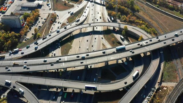 Aerial view the road junction in Kiev. Drone flies back above the highway with driving cars. Ukraine, traffic cross road, view from above with circle road. Top down view of traffic jam, transport