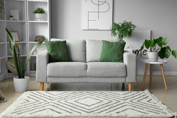 Interior of light living room with cozy grey sofa and houseplants