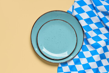 Empty plates and blue checkered tablecloth on beige background