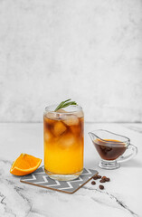Glass of tasty orange espresso and ingredients on table