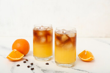 Glasses of tasty orange espresso on white table