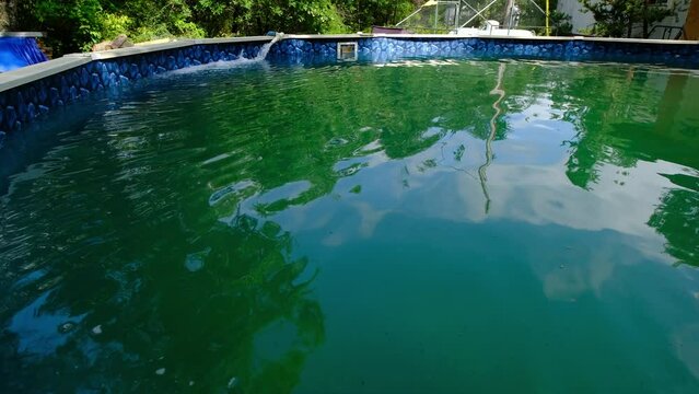 Very green water in the above ground swimming pool full of algae after left without treatment in sunny warm summer days.
