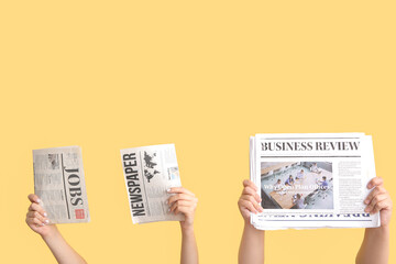 Female hands with different newspapers against color background