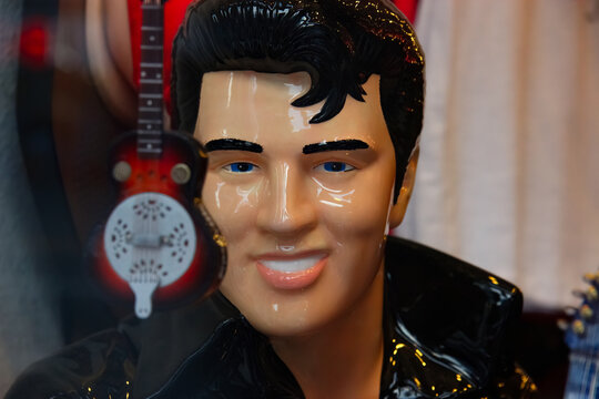 Elvis Presley figurine looking at the camera. The figurine is shiny and a guitar is visible.