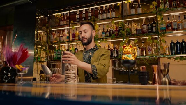 A professional bartender juggles a shaker in his hands. The process of making cocktails in a club at a bar