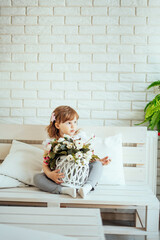 girl sitting on a bed with flowers. White brick wall background