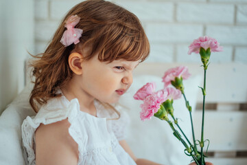 A child smells flowers and makes a face