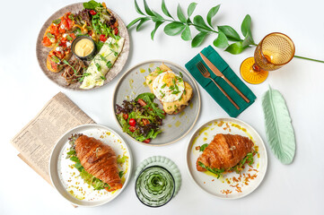 Set of breakfast dishes: croissants, toast, scrambled eggs, salad, bruschetta