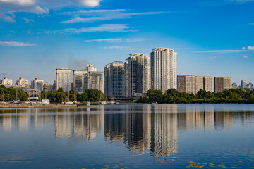 Fototapeta premium Beautiful urban summer landscape: Multi-storey buildings, river and park