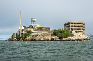 San Francisco, CA, USA - July 12, 2023: Alcatraz Island north tip closeup with tall chimney, water...